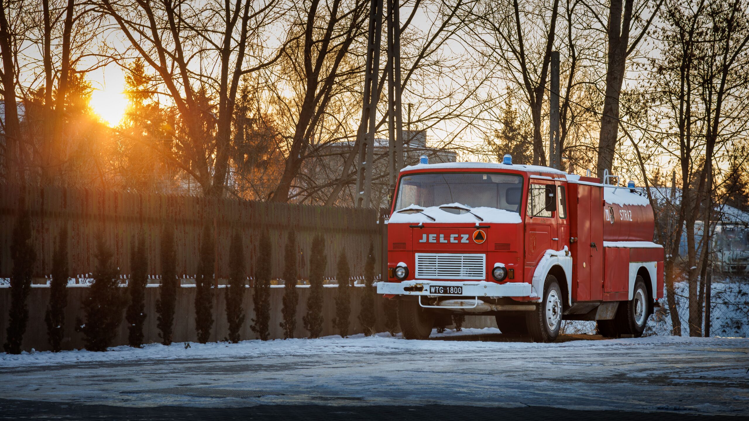Home Red vintage fire truck parked in a snowy landscape at sunset, conveying a nostalgic winter scene.