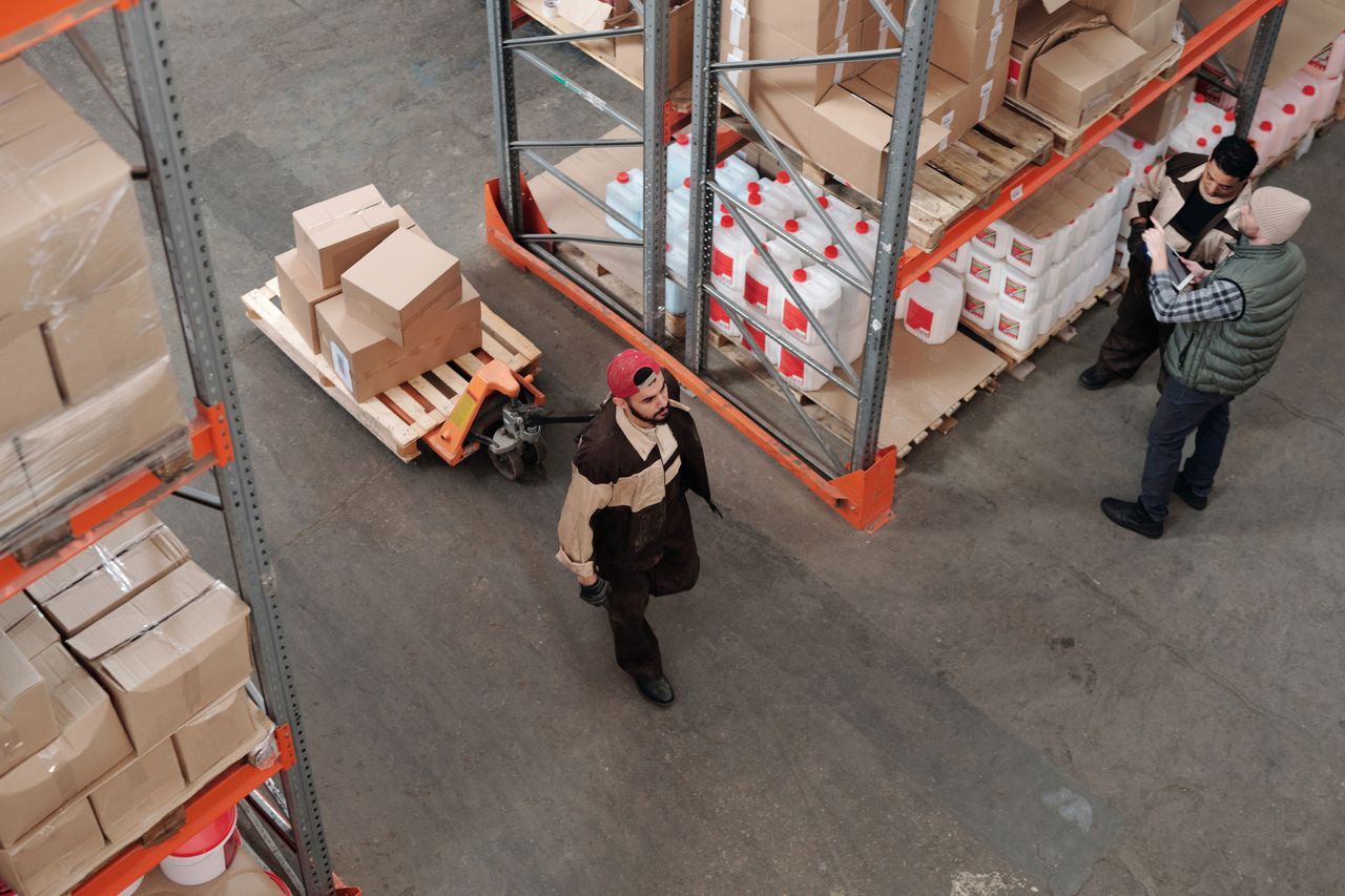 Home Team working in an industrial warehouse discussing and organizing inventory with pallets.