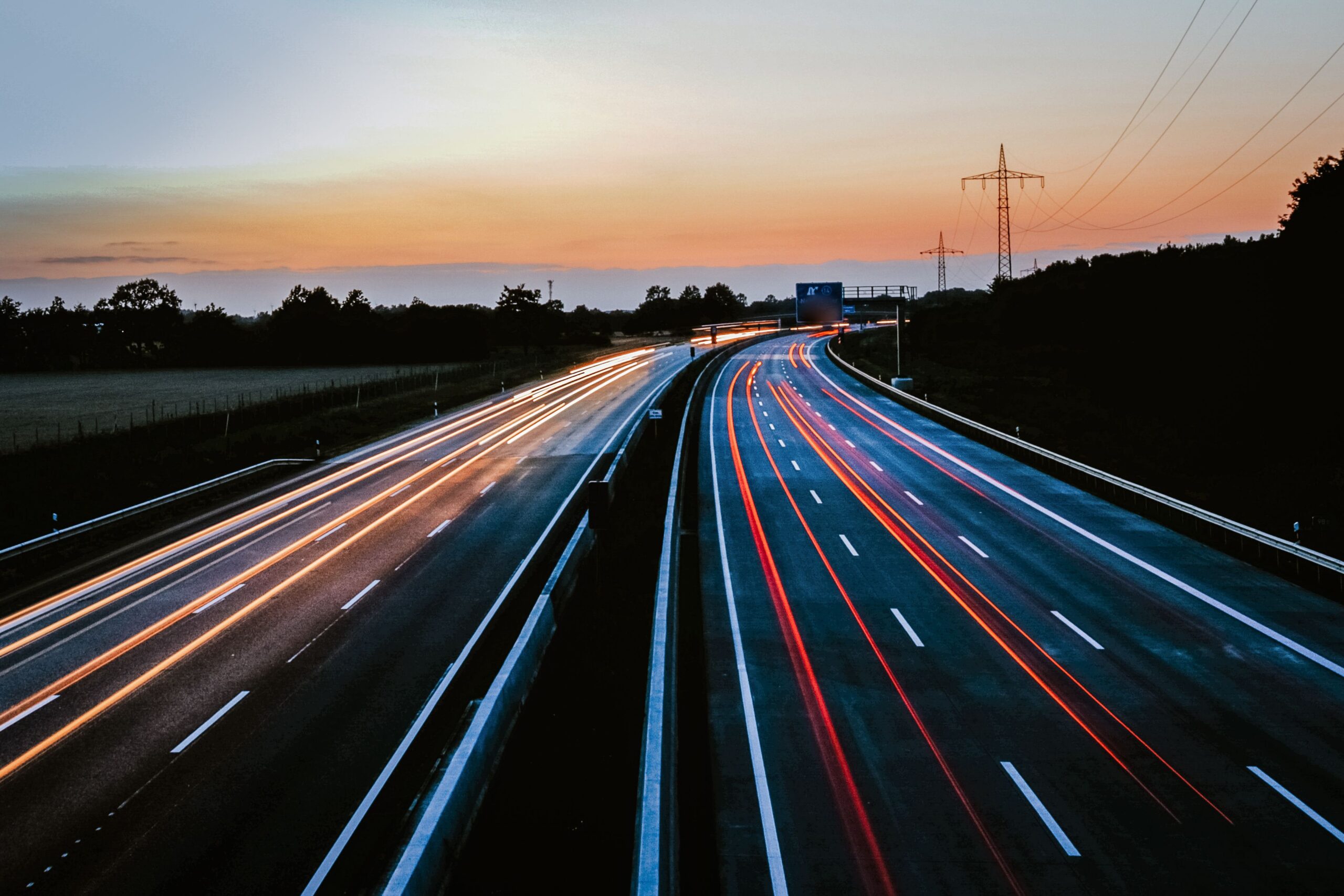 Home Stunning long exposure of light trails on a highway during dusk, showcasing movement and serene skies.