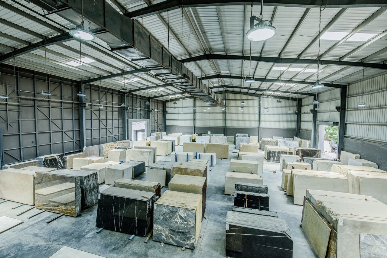 Home Expansive warehouse filled with large stone slabs for industrial use.